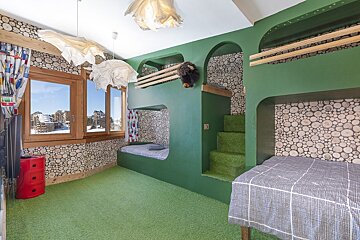A cozy green-themed bunk room with wood accents, astroturf carpet, and log-patterned wallpaper.