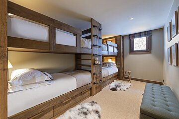 A bedroom with bunk beds and a green ottoman