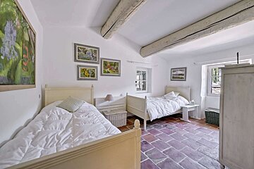 A bedroom with two beds and paintings on the wall