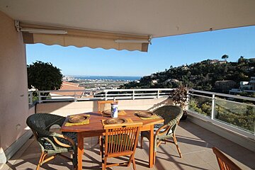 A table and chairs on a balcony overlooking the ocean