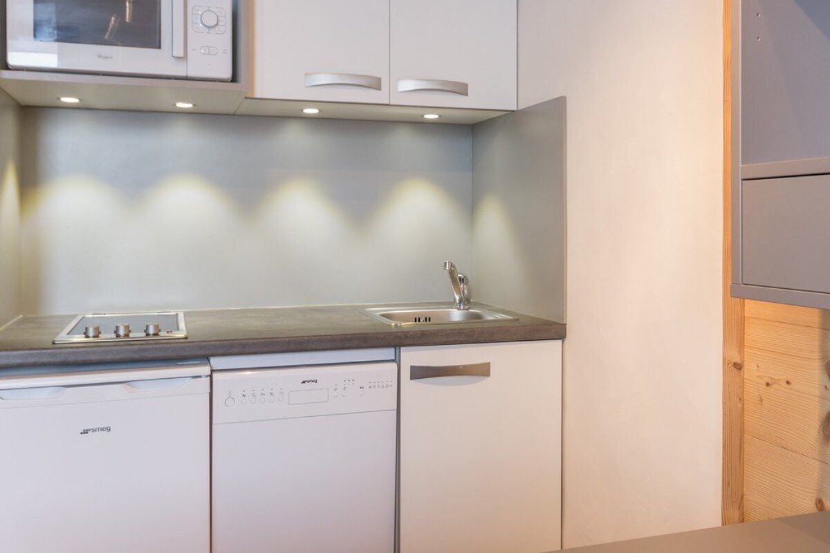 A white smeg dishwasher sits in a small kitchen