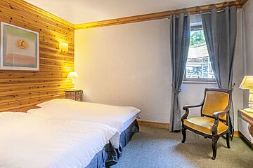 A bedroom with two beds and a yellow chair
