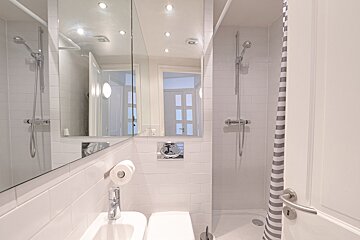 A bathroom with white tiles and a striped shower curtain
