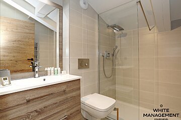 A bathroom with a walk in shower and a rental designer logo