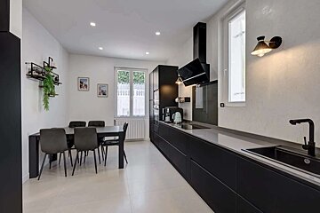 A modern black and white kitchen with a long counter, sleek appliances, and an integrated dining area with a table and chairs.