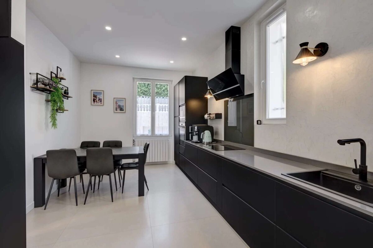 A kitchen with black cabinets and a table and chairs