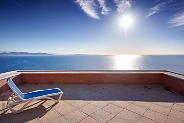 A blue chair sits on a balcony overlooking the ocean