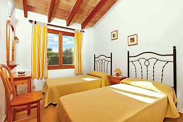 A bedroom with two beds and yellow curtains