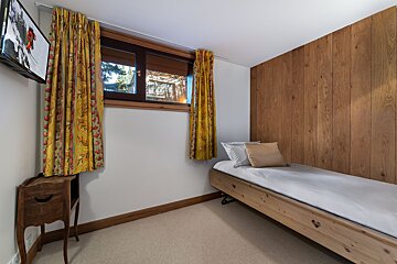 A bedroom with wood paneling and a single bed