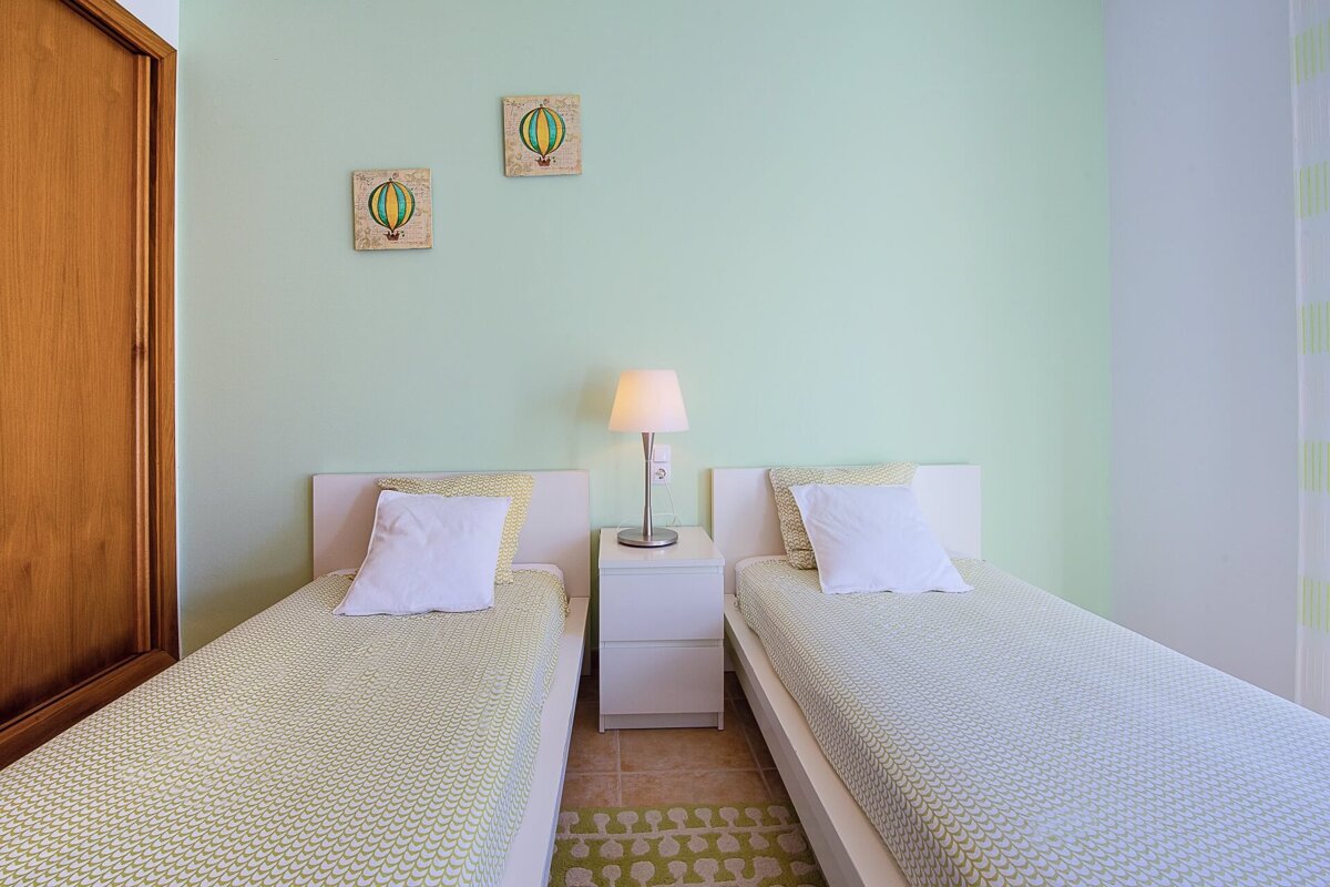 A bedroom with two twin beds and two paintings of hot air balloons on the wall