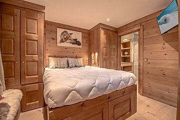 A wooden bedroom with a bed and a picture on the wall