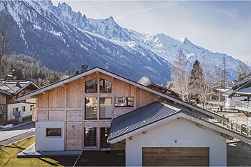 A house in the snow with mountains in the background