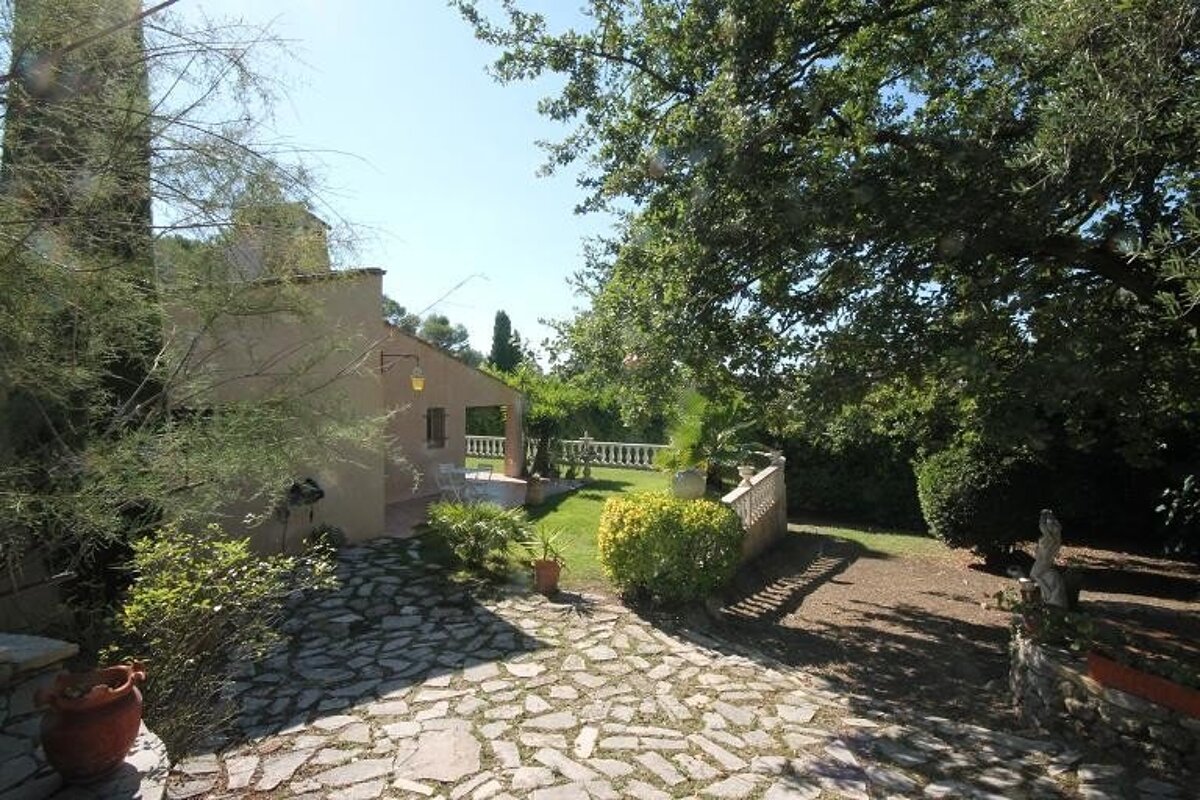 A stone path leads to a house surrounded by trees