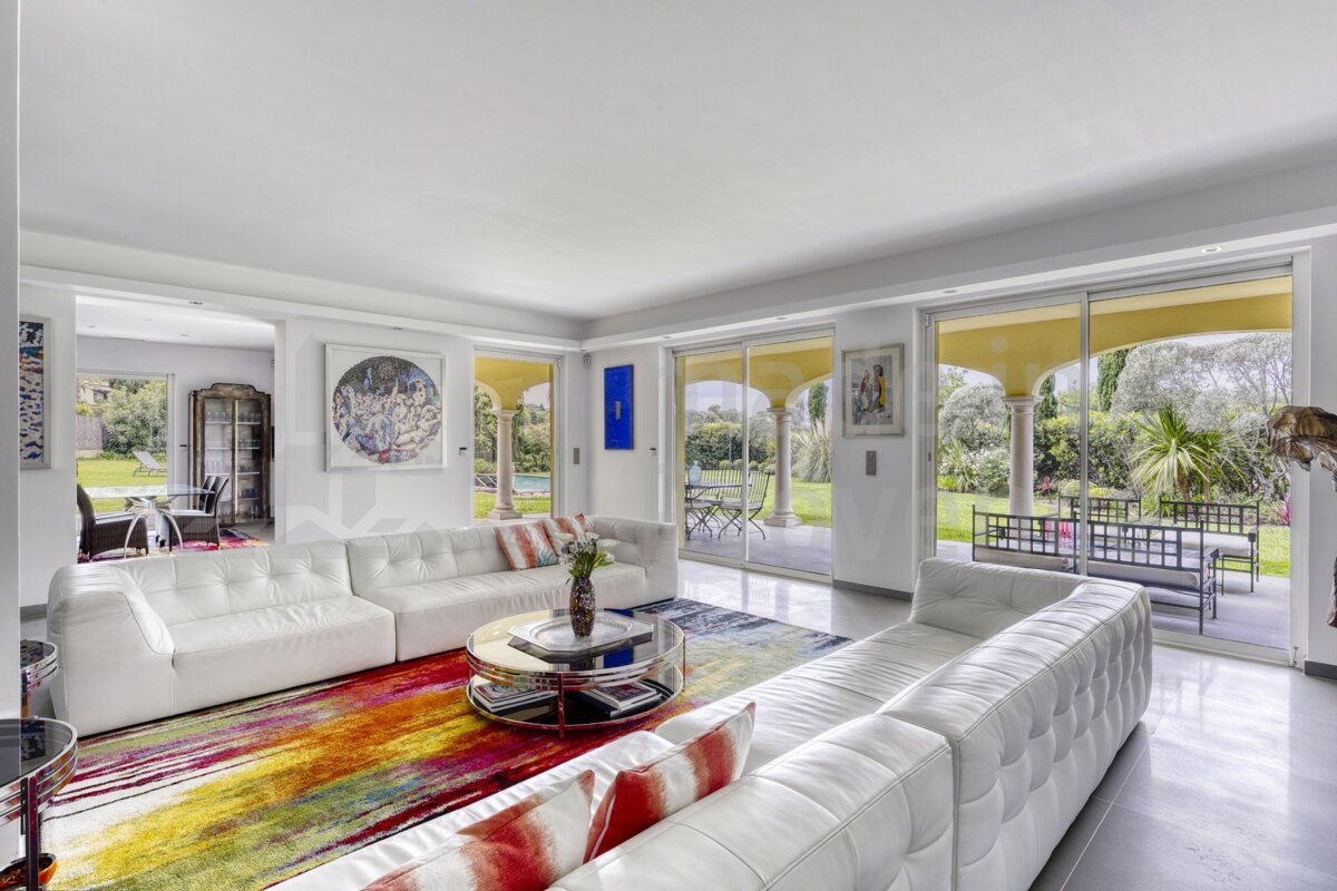 A living room with white furniture and a colorful rug