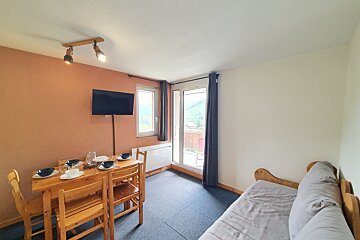A living room with a table and chairs and a flat screen tv