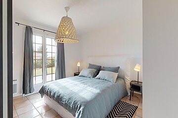 A bedroom with a large bed and a lamp hanging from the ceiling