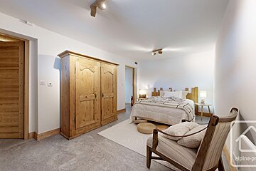 A bedroom with a bed a chair and a wardrobe that says alpine-pro