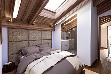 A modern attic bedroom features a wood-paneled vaulted ceiling with a skylight, a bed with neutral bedding, a woven headboard, and an open en-suite vanity.