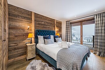 A bedroom with a large bed and a sliding glass door