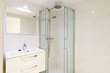 A bathroom with a sink and a shower stall