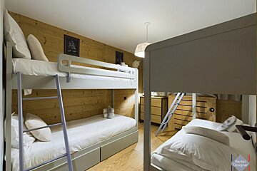A bunk bed with a tv mounted on the wall above it
