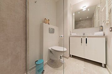 A bathroom with a toilet and a blue trash can