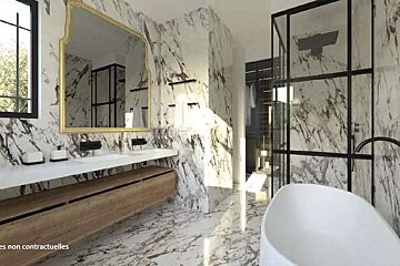 A bathroom with marble walls , two sinks , a bathtub and a large mirror