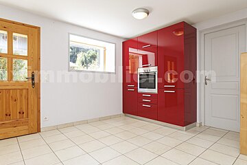 A kitchen with red cabinets and appliances and the website immobilier.com