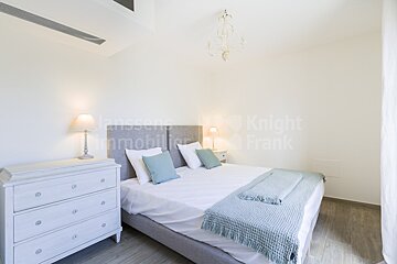 A bedroom with a bed and a dresser with knight frank written on the wall