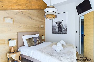 A bedroom with a bed and a picture of a cow on the wall
