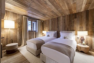 A bedroom with two twin beds and wooden walls