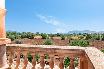 A balcony overlooking a field with mountains in the background