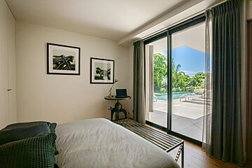 A bedroom with a sliding glass door leading to a pool