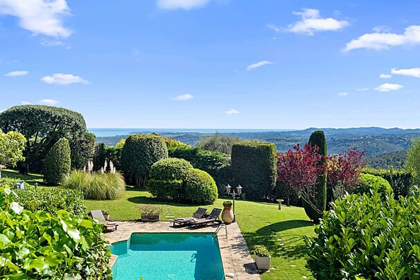 A large swimming pool in the middle of a lush green garden