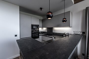 A kitchen with white cabinets and black counter tops