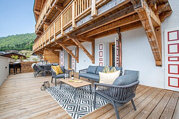 A wooden deck with a couch and chairs on it