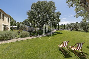 Lawn chairs in a lush green field with a house in the background