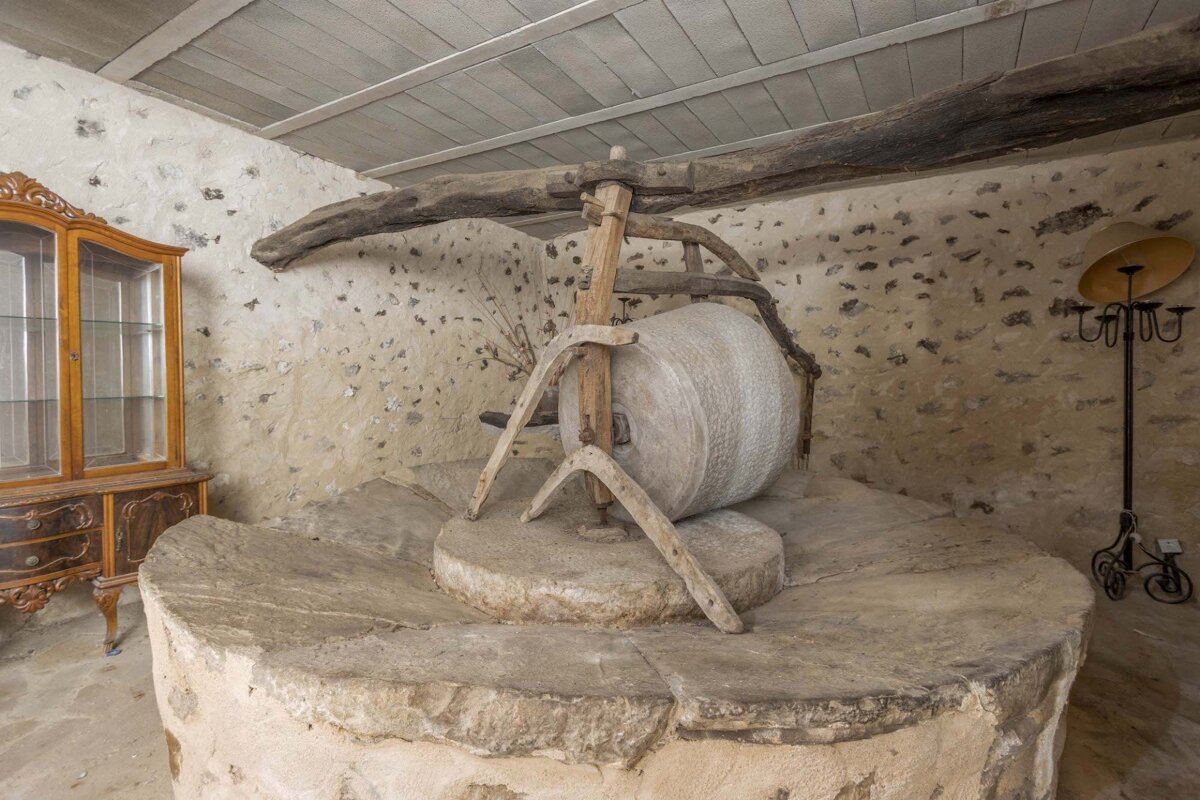 A large stone wheel with a wooden handle sits in a room