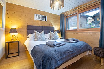 A bedroom with a large bed and a picture of trees on the wall