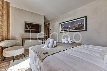 A bedroom with a large bed and a picture of mountains on the wall