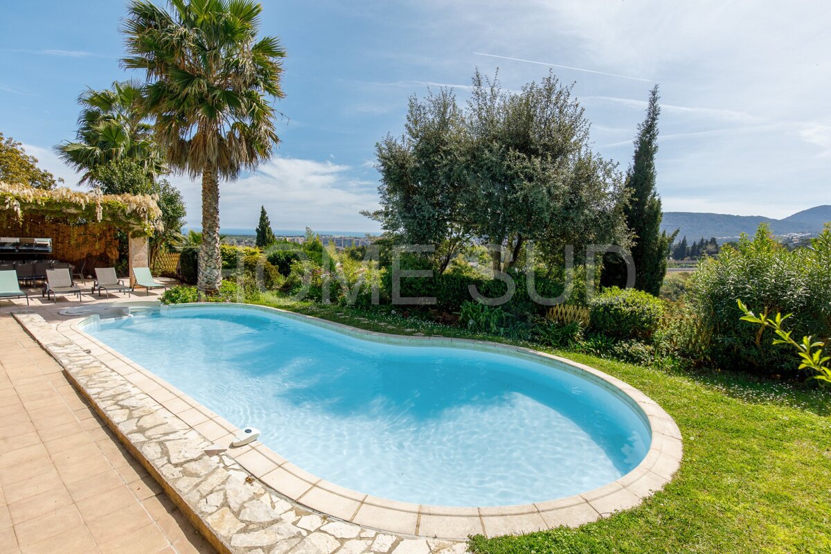 A large swimming pool is surrounded by a lush green lawn and a sign that says home sud