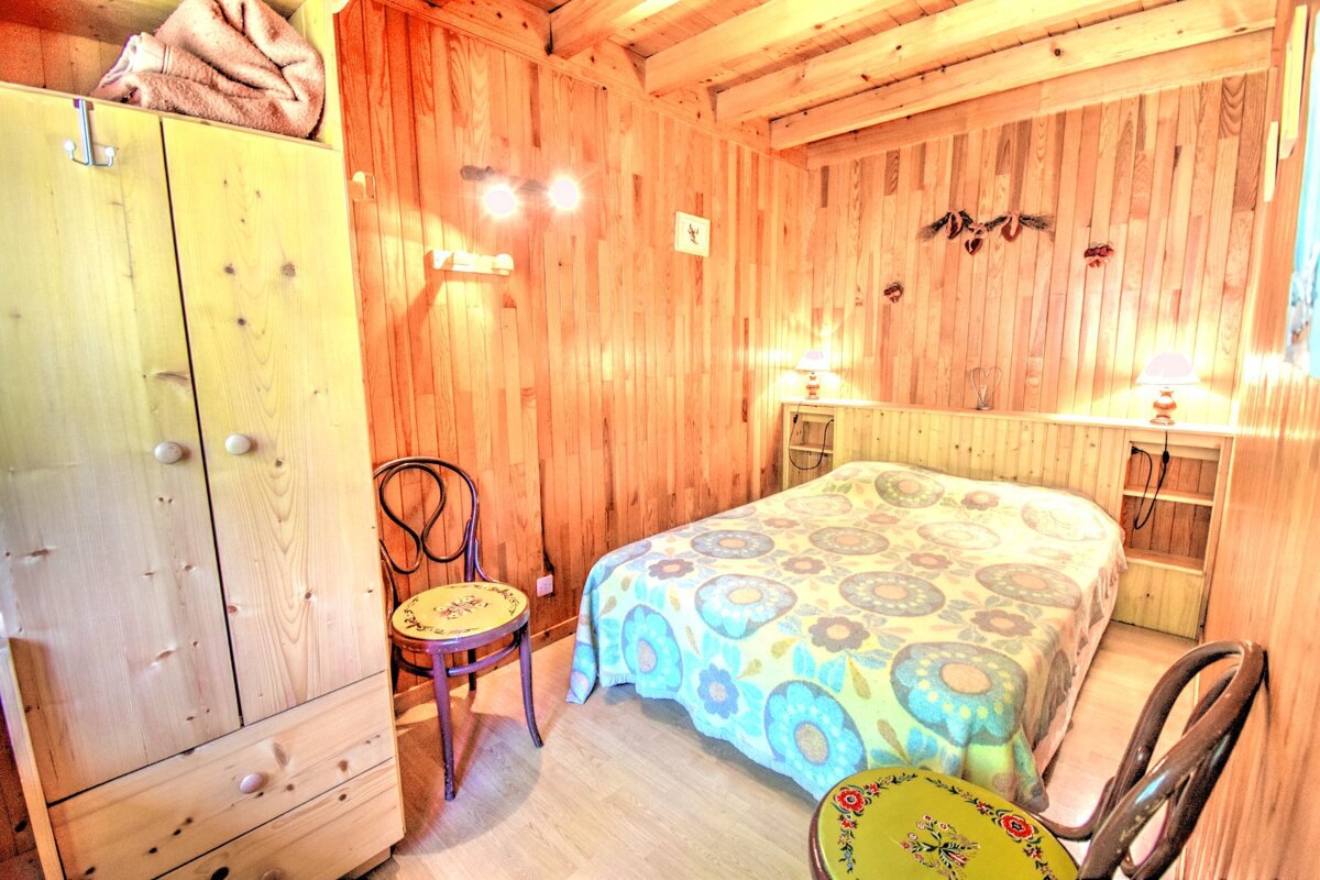 A wooden bedroom with a bed and a chair
