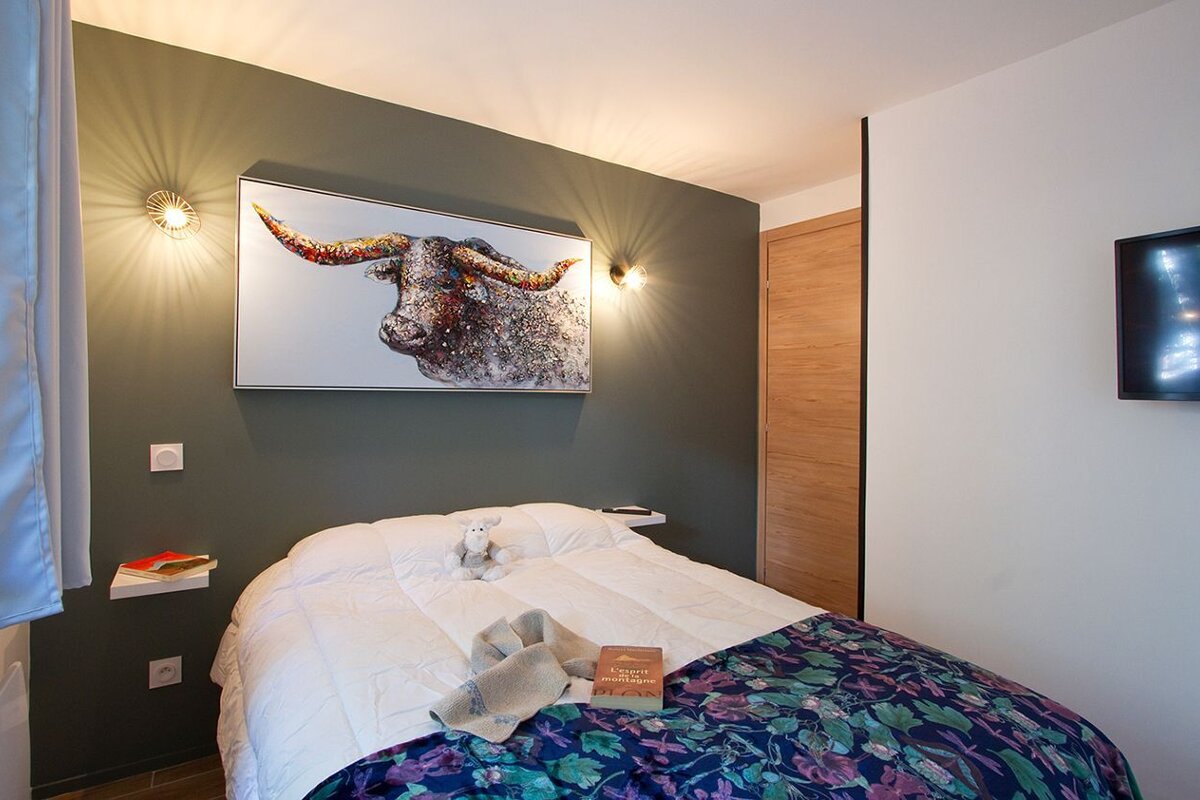 A bedroom with a painting of a bull on the wall above the bed