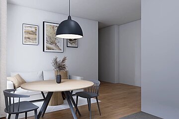 A modern dining area featuring a round light-wood table with grey chairs, a black pendant light, and a white sofa in the background.