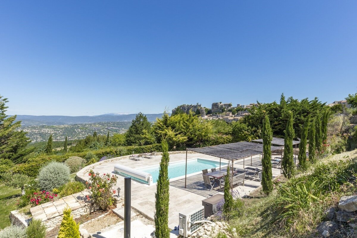 A large swimming pool is surrounded by a lush green landscape