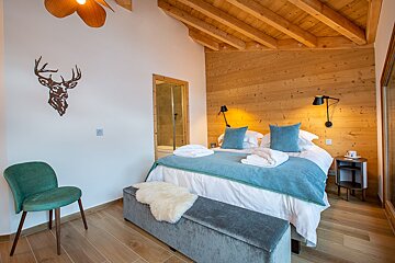 A bedroom with a deer head on the wall above the bed