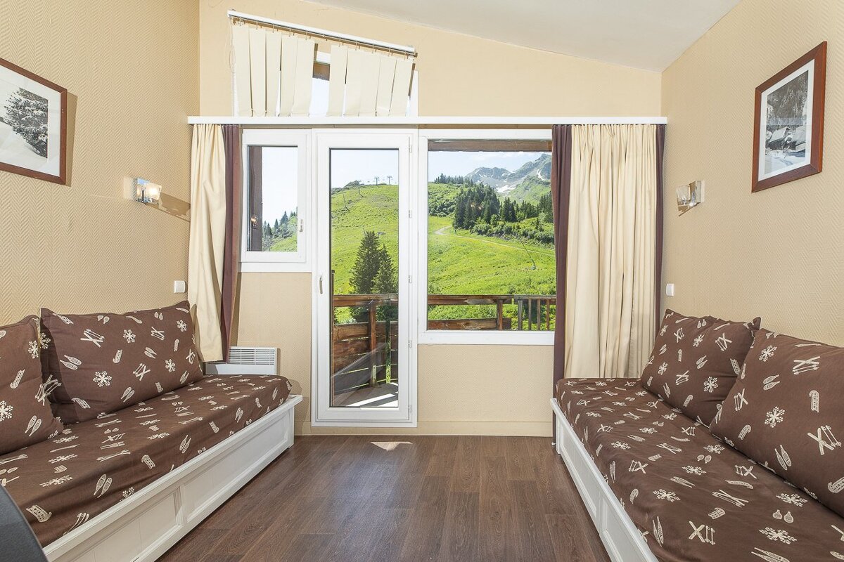 A room with a couch and a window with mountains in the background