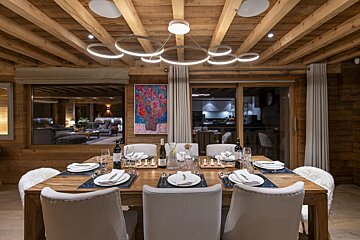 A dining room with a table and chairs and a painting on the wall