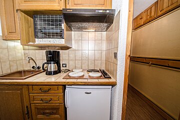 A small kitchen with a small fridge and a coffee maker