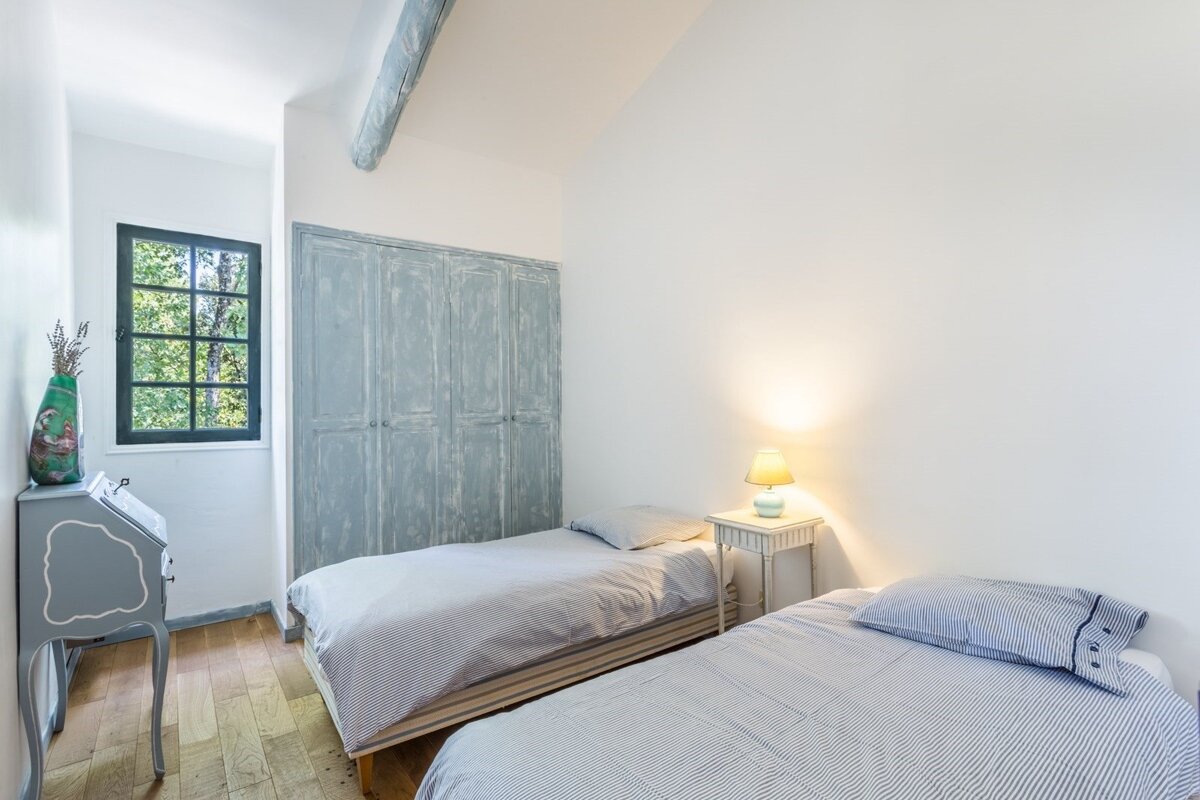 A bedroom with two beds and a lamp on the nightstand